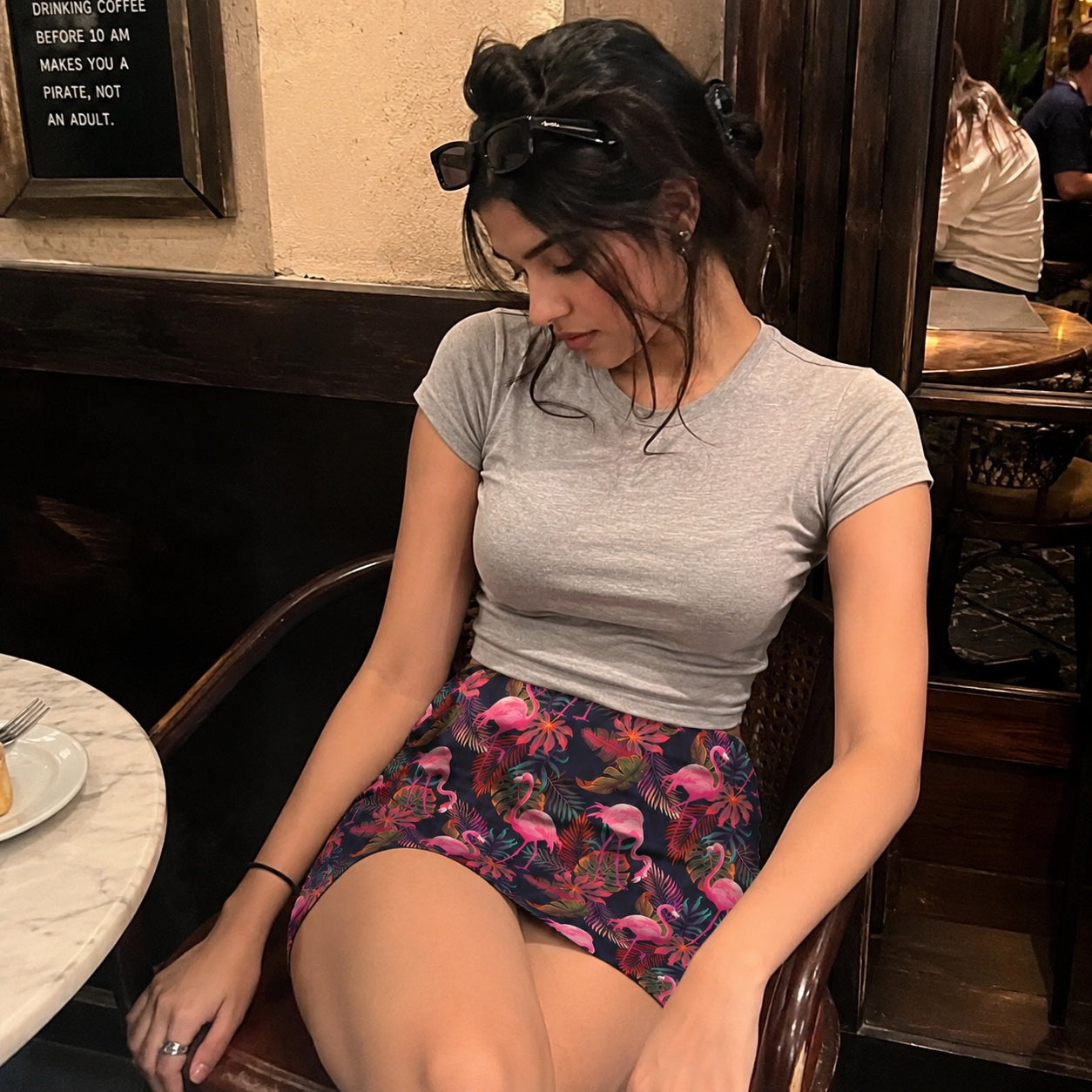 Woman sitting in a cafe wearing a gray t-shirt and colorful flamingo skirt.