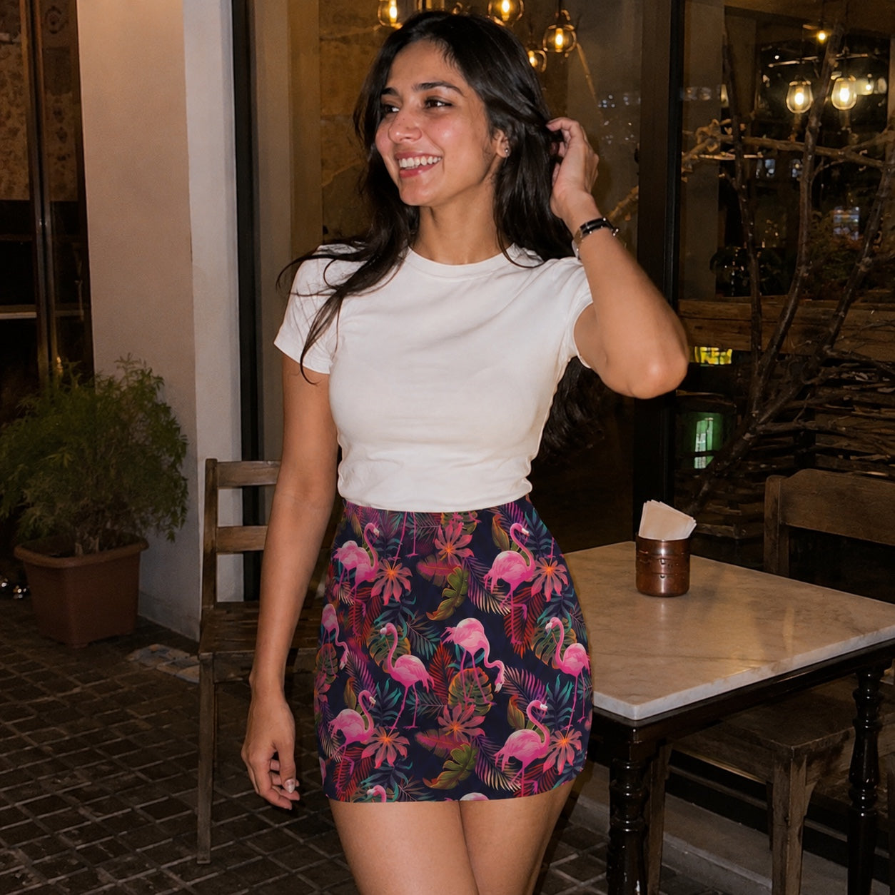 Woman in a white top and colorful Flamingo skirt standing in an indoor setting.
