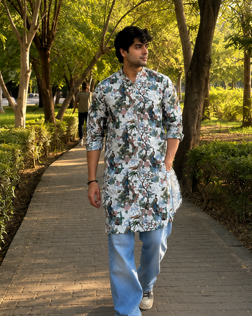 Man walking on a path in a park wearing a floral shirt and blue jeans.