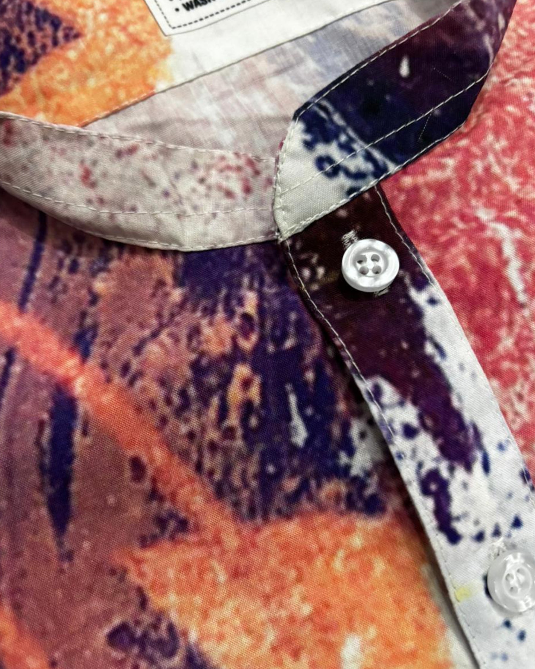 Close-up of a kurta with a colorful pattern and button detail.