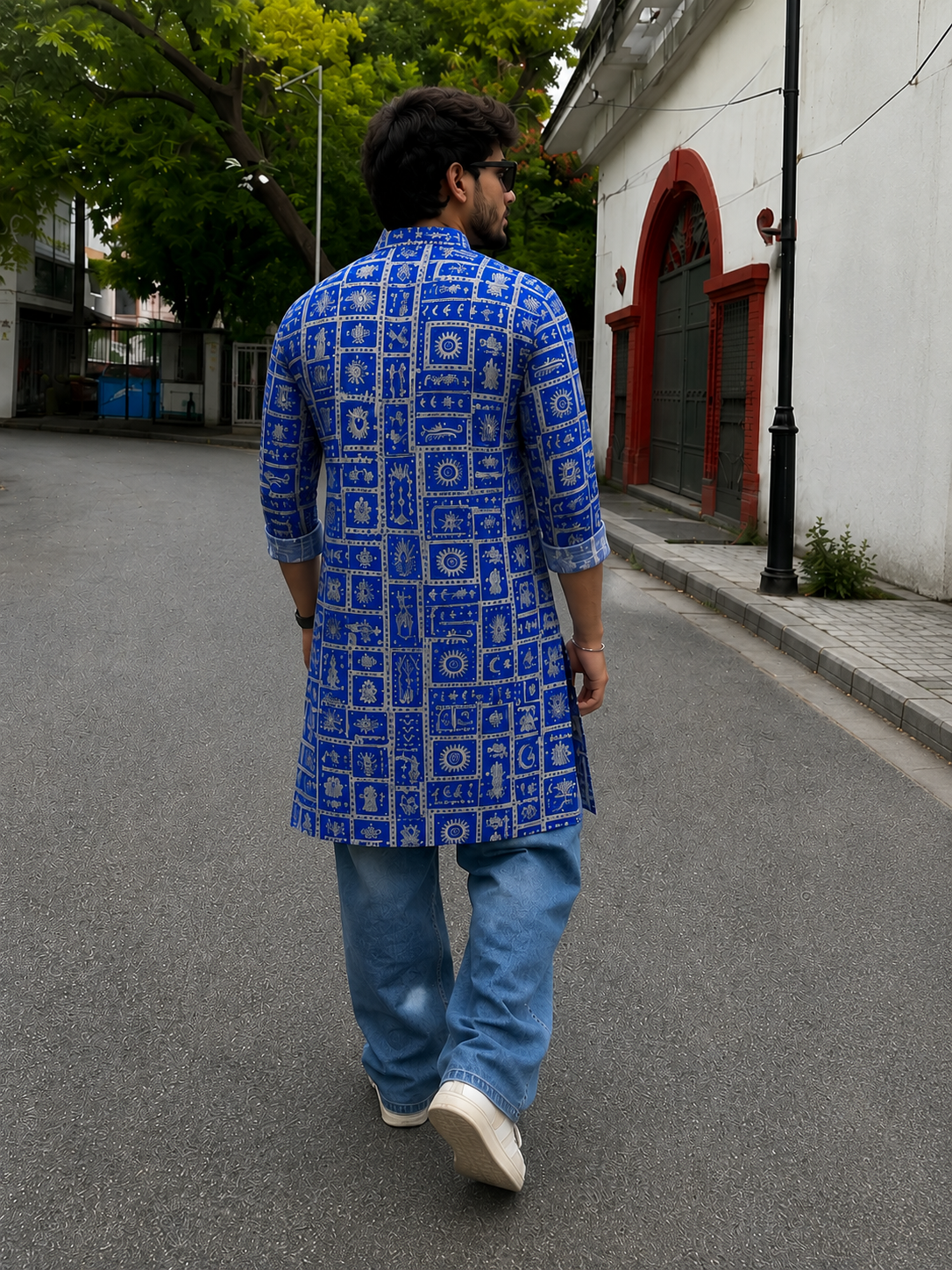 Man wearing a blue patterned kurta walking on a street.