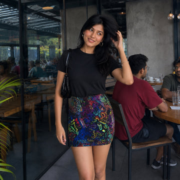 Woman posing in a acid trip  skirt and black top in a restaurant setting