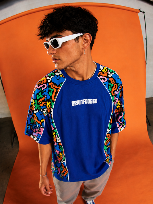 Person wearing a colorful shirt with 'Brainfogged' logo against an orange backdrop