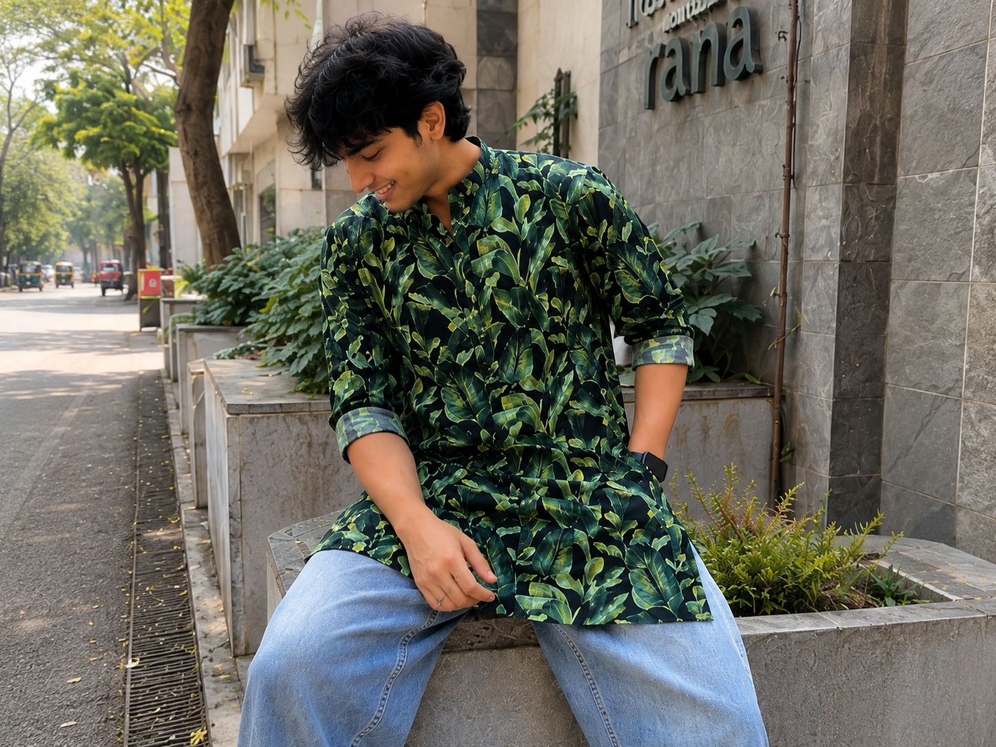 Person wearing a green leaf-patterned kurta  sitting on a bench outdoors.