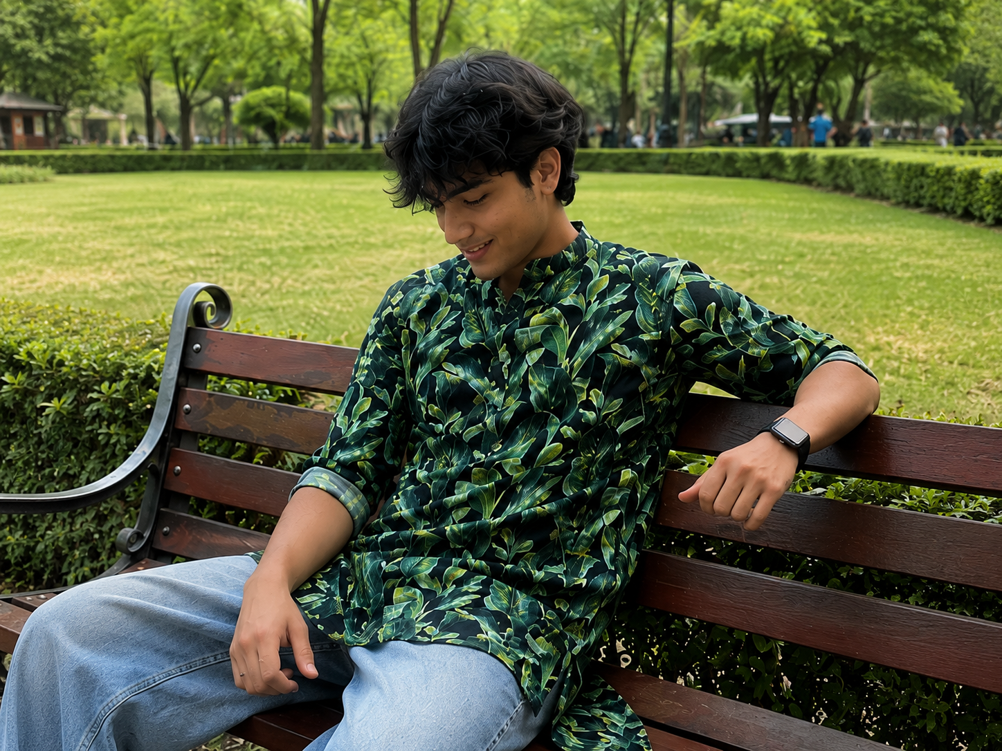 Person wearing a green patterned kurta sitting on a bench in a park.