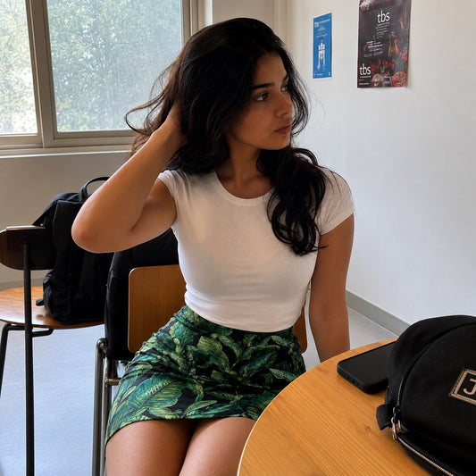 Woman sitting at a table in a casual setting with a phone and bag on the table.