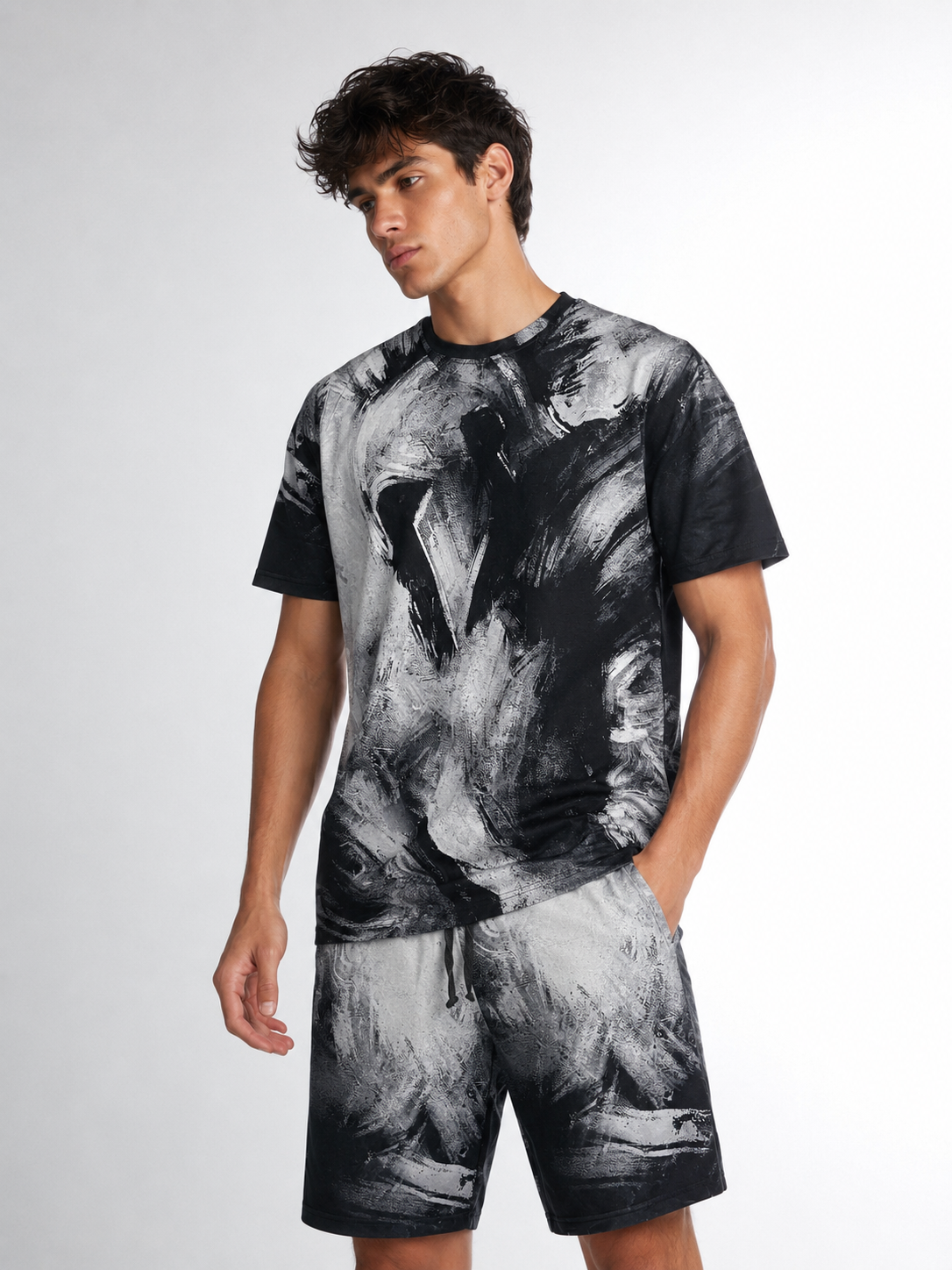 Man wearing a black and gray tie-dye t-shirt and shorts on a white background