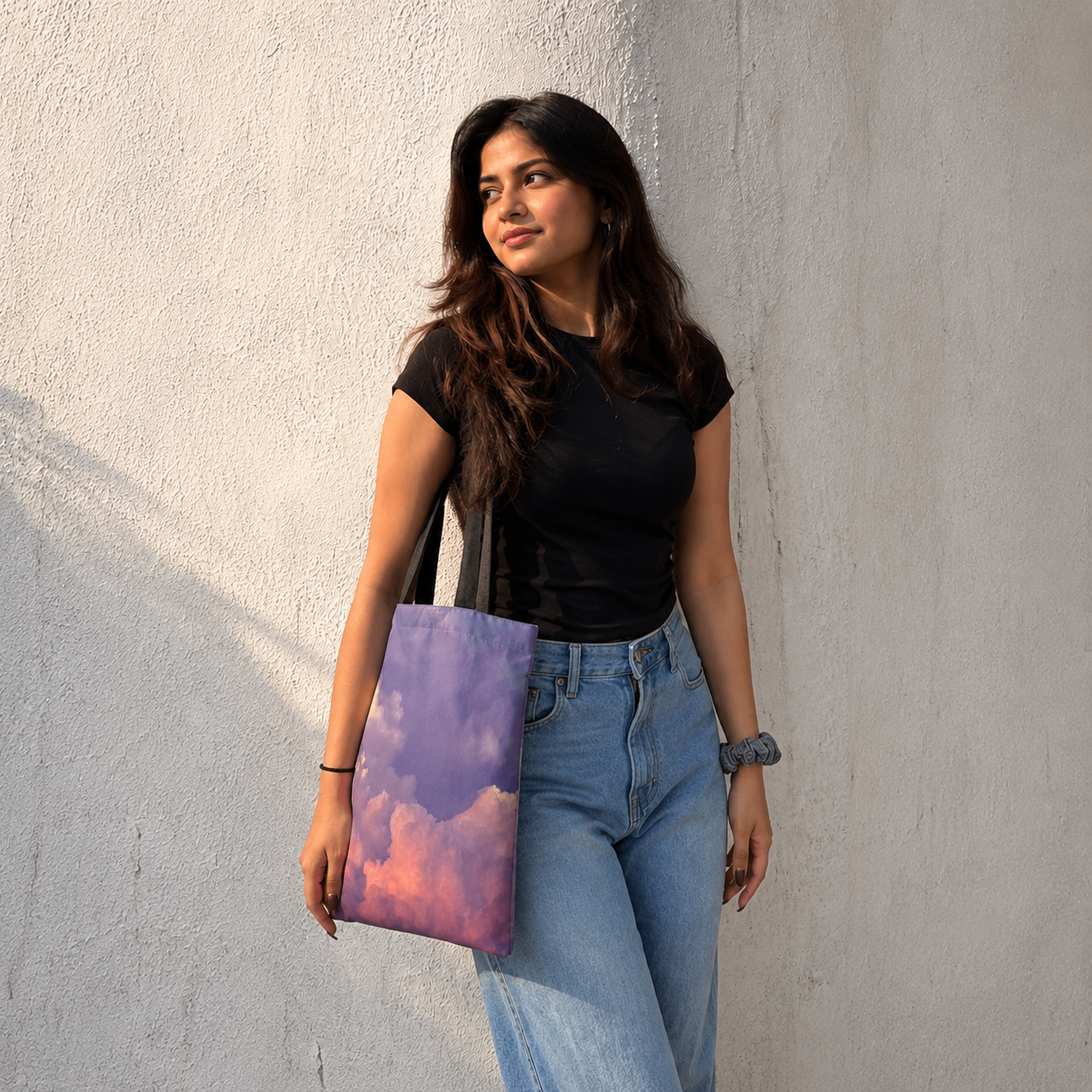 Woman holding a colorful tote bag against a light gray wall