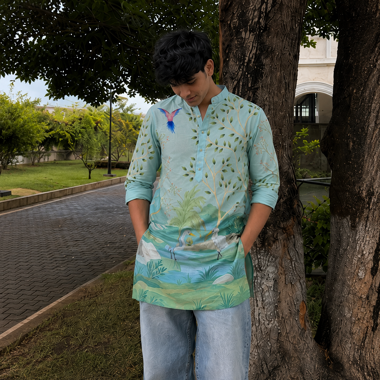 Person wearing a colorful shirt leaning against a tree in an outdoor setting