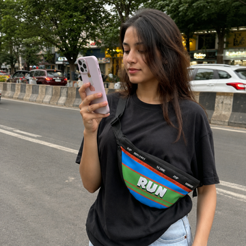 Woman holding a phone on a street with a colorful bag over her shoulder