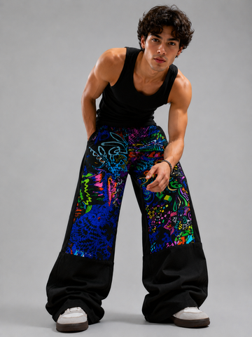Person wearing a black tank top and colorful pants on a gray background
