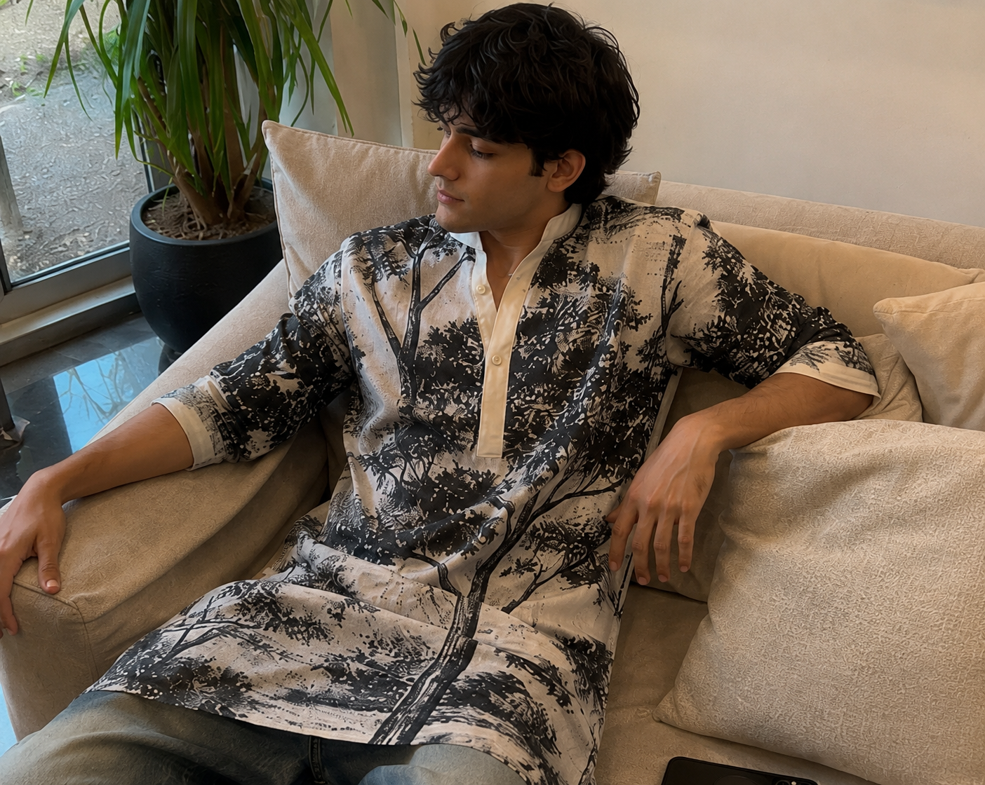 Person sitting on a couch wearing a black and white patterned shirt in a living room.